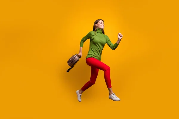 Foto de perfil de cuerpo completo de la señora bonita funky saltando alto sosteniendo el bolso joven fresco corriendo a casa después de estudiar desgaste casual verde jersey pantalones rojos aislado color amarillo fondo —  Fotos de Stock