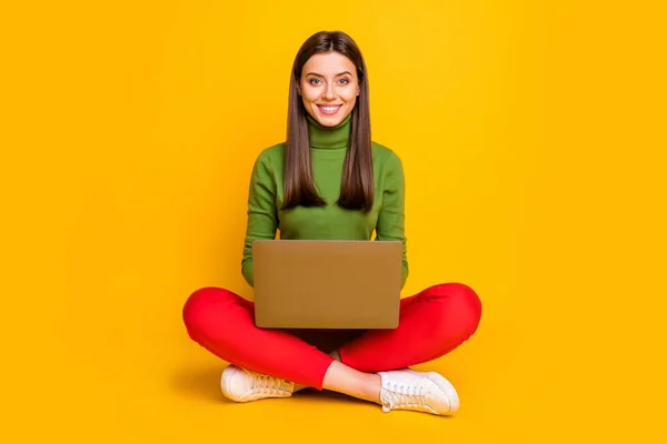 Фото красивой дамы сидя пол с ноутбуком смотреть онлайн лекцию написания творческой композиции писатель начинающий носить зеленый свитер красный брюки изолированный желтый цвет фона — стоковое фото