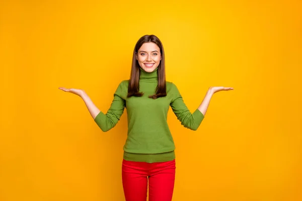 Portret van positieve vrolijke meisje houden hand maatregel advertenties huidige promotie kortingen dragen stijlvolle broek geïsoleerd over gele kleur achtergrond — Stockfoto