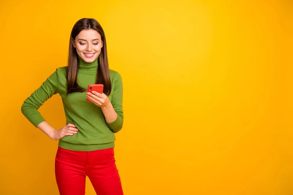 Retrato de menina alegre positiva usando o smartphone lendo notícias de mídia social conversando com amigos usam roupas elegantes isoladas sobre fundo de cor amarela — Fotografia de Stock