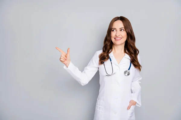 Portrait von ihr sie schön attraktiv fröhlich wellig behaarte Sanitäter trägt Mantel Phonendoskop Stethoskop zeigt Kopierraum Look Idee isoliert über grauen Pastellfarben Hintergrund — Stockfoto