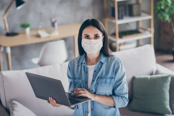 Portret van positief meisje zelf quarantaine corona virus infectie werk thuis kantoor gebruik laptop dragen medisch masker jeans shirt in huis binnen — Stockfoto