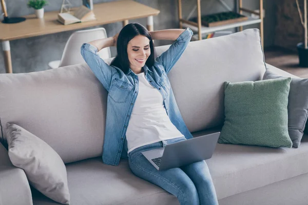 Retrato de chica positiva gerente de trabajo casa corona virus cuarentena sit divan use laptop ver película en lugar de leer documento proyecto de desgaste traje de mezclilla en casa interior apartamento —  Fotos de Stock