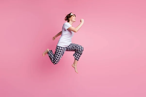 フルサイズプロフィール写真の面白い女性ジャンプ高ラッシュ販売ショッピングを変更していない睡眠服を着用マスク白いTシャツ再生パジャマパンツ裸足で隔離されたピンク色の背景 — ストック写真