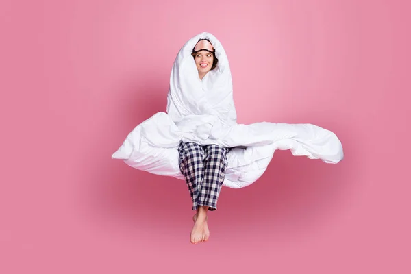Full storlek foto av glad dam sent på morgonen sitta sängen håll runt huvudet varm filt ser tomt utrymme bära mask vit rutig pyjamas byxor barfota isolerad rosa färg bakgrund — Stockfoto