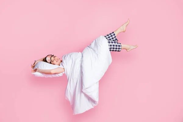 Полная длина фото красивой леди наслаждаться дремотой лежащей кровати подушку одеяло сон ходить поднять ноги до пустого пространства носить маску белый пижама футболка брюки босиком изолированный розовый цвет фона — стоковое фото