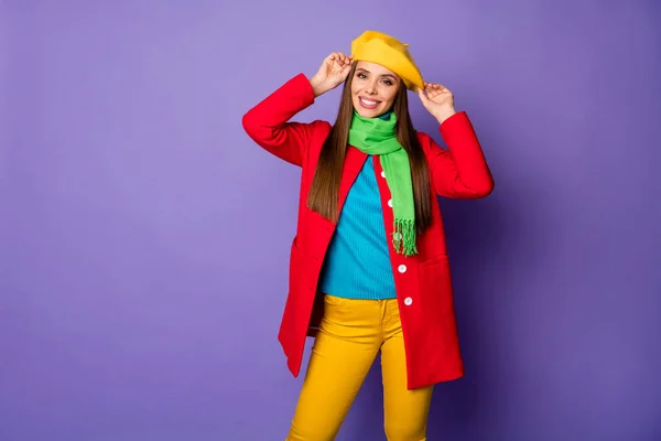 魅力的な可愛い女性の歯の笑顔良い気分は、現代の黄色ベレー帽ブルータートルネックグリーンスカーフ赤ロングコートパンツ孤立紫色の背景を身に着けている — ストック写真