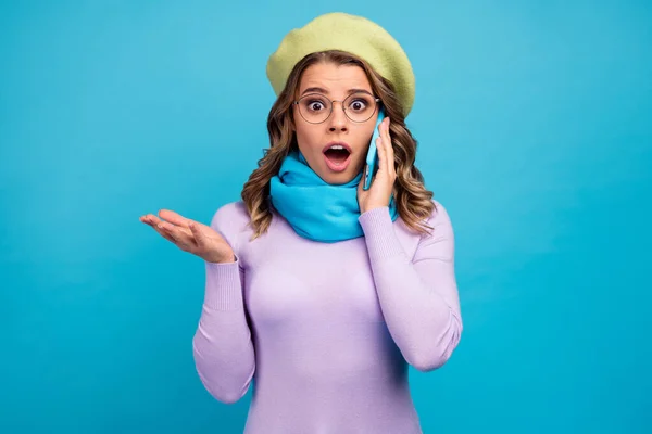 Omg increíble. Sorprendido chica llamada amigo smartphone escuchar información privada confidencial impresionado grito desgaste elegante moda violeta jersey headwear aislado color azul fondo — Foto de Stock