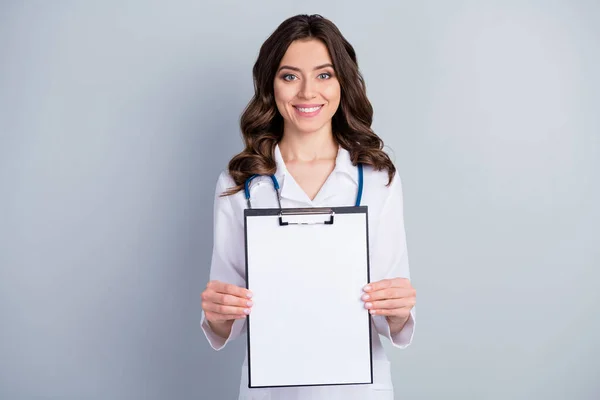 Портрет кваліфікованого лікаря-терапевта кардіолога, який тримає дошку для кліпу, показує, як корона вірус ліки за рецептом носить біле пальто уніформу ізольовано на сіро-кольоровому фоні — стокове фото