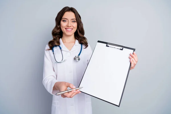 Портрет позитивної кваліфікованої жінки-кардіолога, яка тримає дошку для кліпу, показує місце для перо, запитайте знак корона вірус рецепт ліки носити біле пальто уніформу ізольовано на сіро-кольоровому фоні — стокове фото