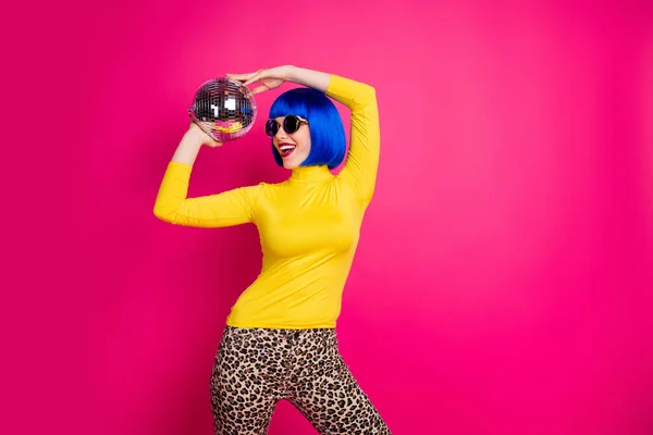 Foto de funky chica bonita fiesta estudiantil club nocturno celebrar bola disco por encima de la cabeza desgaste especificaciones cuello alto amarillo azul peluca corta pantalones de leopardo aislado color rosa brillante fondo —  Fotos de Stock