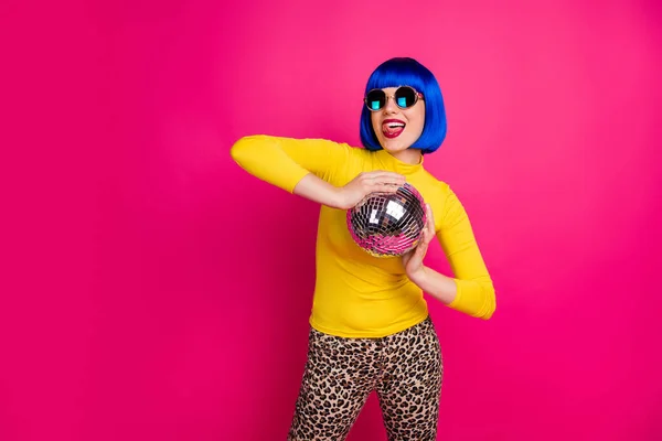 Fotografie bláznivý clubber dáma student strana držet disco míč lízání rty nosit specifikace žlutá rolák modrá bob paruka leopard kalhoty izolované pulzující růžová barva pozadí — Stock fotografie
