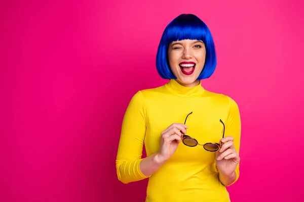Фото привлекательной забавной леди современный взгляд сияющий улыбка моргание глаза провести ретро-спецификации носить стильный желтый водолазка синий короткий синий парик изолированы яркий розовый цвет фона — стоковое фото