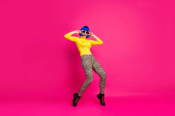 Plná velikost fotografie legrační dáma tanec studentská strana V-znamení symboly v blízkosti očí nosit specifikace žlutá rolák modrá paruka boty leopard kalhoty izolované světlé růžové barvy pozadí — Stock fotografie