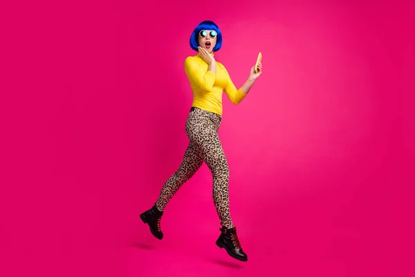 Full body profile photo of crazy funny lady skok vysoký chůze ulice procházení telefonu oblečení specifikace žlutá rolák modrá bob paruka boty leopard kalhoty izolované světlé růžové barvy pozadí — Stock fotografie
