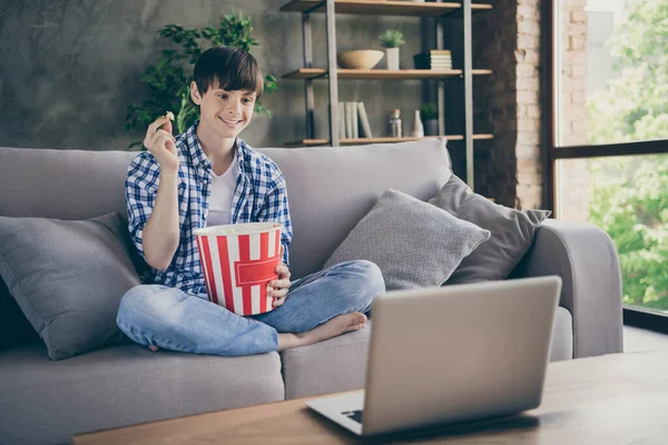Фото школьника-подростка, сидящего на удобном диване, сидящего дома на карантине и смотрящего онлайн-фильм о блокноте. — стоковое фото