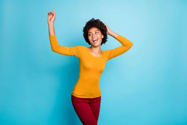 Portrait of wild cheerful positive youth afro american girl clubber dance in night club raise arms scream look copyspace wear red pants sweater isolated over blue color background — Stock Photo, Image