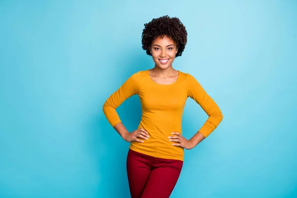 Retrato de encantadora chica afroamericana bastante agradable disfrutar de vacaciones de primavera otoño tiempo libre poner las manos cintura desgaste suéter de buen aspecto aislado sobre fondo de color azul — Foto de Stock