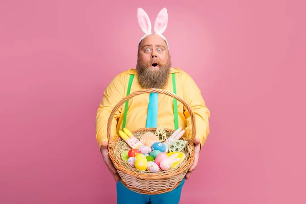 Retrato de su agradable sorprendido impresionado funky contento barbudo sujeto en las manos que le da festal Pascua artesanal cesta panadería snack aislado sobre rosa pastel color fondo —  Fotos de Stock