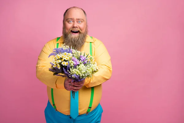 Ritratto del suo bel affettuoso attento funky felice ragazzo barbuto positivo che ti dà fiori freschi congratulandosi isolato su sfondo rosa pastello — Foto Stock
