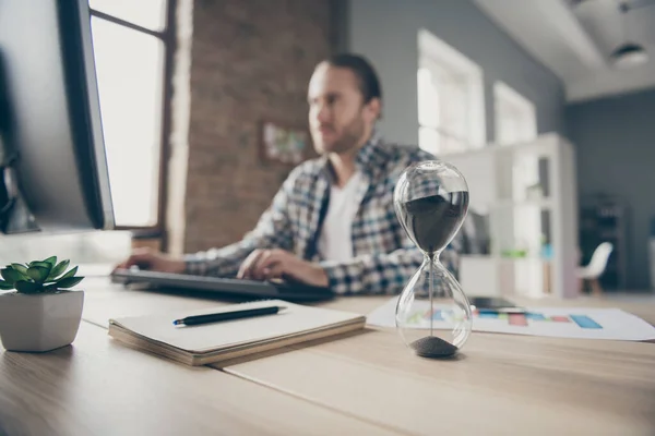 Fuoco sfocato foto di bel ragazzo d'affari guardare computer monitor orologio a sabbia sul tavolo chattare capo promessa finire rapporto nel tempo indossare abito camicia casual seduta sedia ufficio al chiuso — Foto Stock