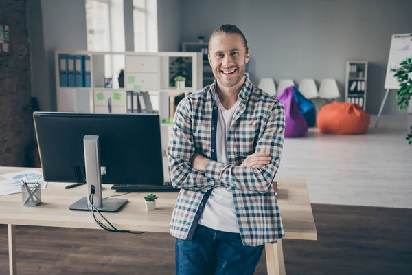 照片中英俊的企业管理者男人靠着桌子胳膊交叉自信的人友善的微笑穿着休闲装站在宽敞的现代室内办公室 — 图库照片