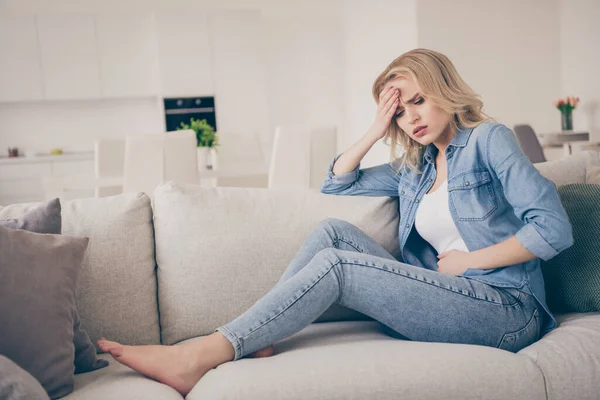 Profile photo of unwell displeased blond lady sitting couch stay home quarantine hold hand belly forehead suffer stomach ache pms have headache modern interior living room indoors — Stock Photo, Image