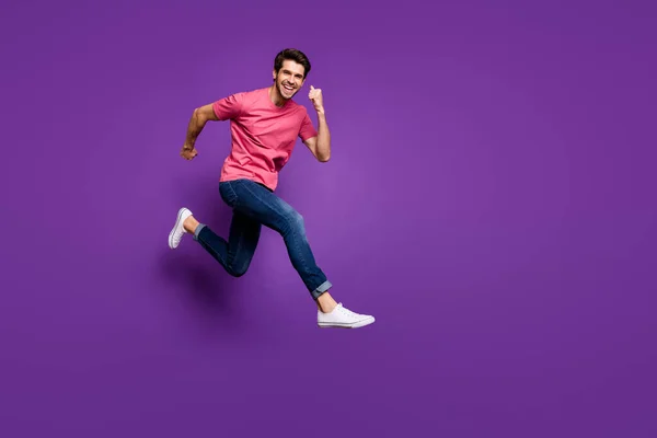 Фотографія профілю красивого привабливого хлопця, який стрибає високо вгору торгового центру, ціни на продаж одягаються випадкові рожеві футболки джинси взуття ізольовані фіолетового кольору фону — стокове фото