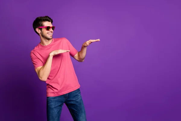 Foto de cara atraente bonito jovem millennial dança movimentos estranhos irradiando sorrindo usar óculos de sol casual rosa camiseta azul jeans isolado cor roxa fundo — Fotografia de Stock