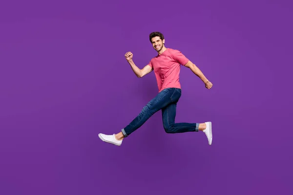 Teljes hosszúságú profilkép vonzó srác ugrás nagy sebességű bevásárlóközpont eladási árak viselnek alkalmi rózsaszín póló farmer lábbeli elszigetelt lila színű háttér — Stock Fotó
