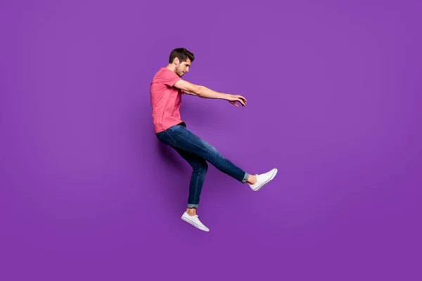 Фотография парня в профиль в полный рост, на которой он прыгает с ветерком, падая с невесомости, одевается в красивую одежду и обувь на ярком цветном фоне — стоковое фото