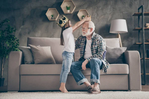 Profile photo of funny aged old grandpa golden crown head little pretty granddaughter playing famous people roles stay home quarantine safety modern interior living room indoors
