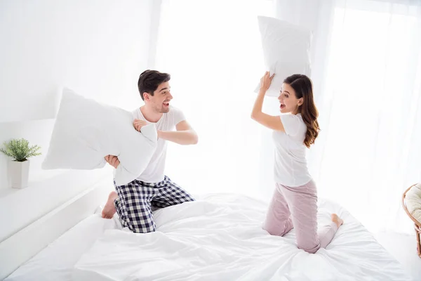 Foto de funky linda dama alegre guapo chico casado pareja jugando almohada pelea sábanas cama disfrutar fin de semana sábado por la mañana buen estado de ánimo excitado desgaste pijama habitación interior —  Fotos de Stock