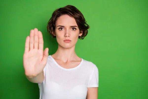 Foto van mooie ernstige dame verhogen hand tonen negatieve reactie zeggen geen stoppen met het doden van dieren vervuiling milieu vrijwilliger dragen witte t-shirt geïsoleerde groene kleur achtergrond — Stockfoto