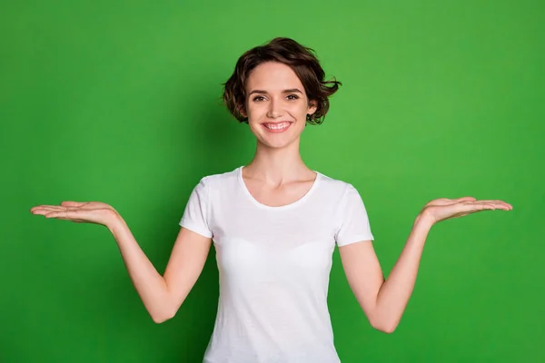 Foto de atraente senhora ondulado penteado segurar dois braços abertos espaço vazio demonstrar novidade aconselhando escolher um melhor gerente de venda desgaste casual branco t-shirt isolado cor verde fundo — Fotografia de Stock