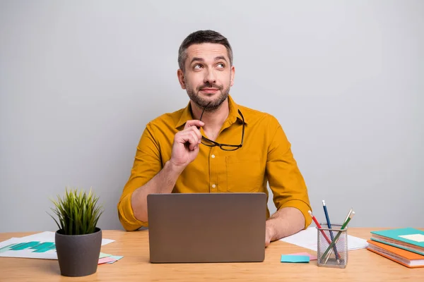 Retrato de sueño administrador de ensueño ceo hombre sentarse escritorio celebrar gafas mirada copyspace pensar pensamientos imaginar corona virus cuarentena extremo sentarse escritorio aislado sobre fondo de color gris — Foto de Stock