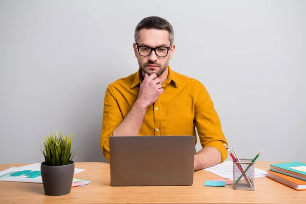 Retrato de hombre de mente seria sentarse mesa de trabajo casa portátil leer colegas proyecto sentirse pensativo analizar trabajo casa desgaste amarillo camisa aislada sobre fondo de color gris — Foto de Stock