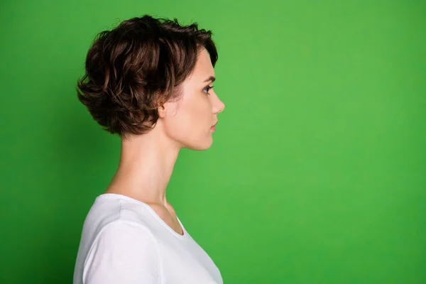 Nahaufnahme Profilfoto von attraktiven Dame kurze wellige Frisur nicht lächelnd aussehen Seite leeren Raum konzentriert tragen lässig weißes T-Shirt isoliert grüne Farbe Hintergrund — Stockfoto
