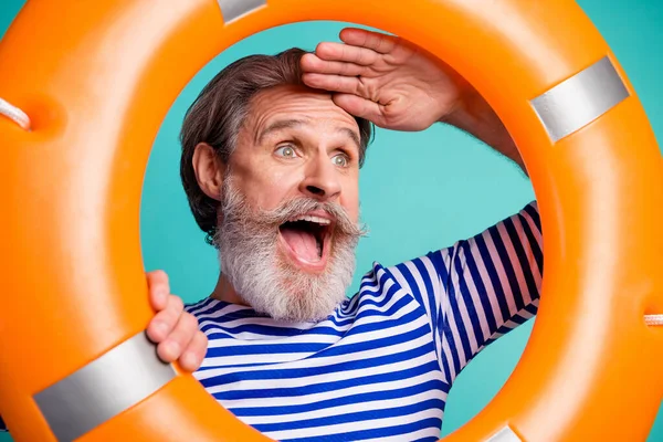 Toprak. İlgilenen komik yaşlı adamın yakın plan fotoğrafı denizci ağzı açık turist can simidinin içine bak uzaktan seyret çizgili denizci gömleği giy izole edilmiş deniz mavisi arkaplanı — Stok fotoğraf