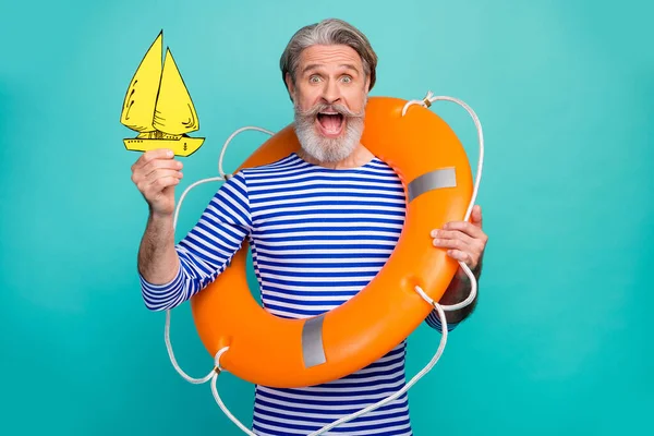 Foto de atraente moda envelhecido marinheiro boca aberta segurar segurança vida bóia amarelo pintado papel mar oceano barco desgaste listrado marinheiro camisa vestido isolado teal cor fundo — Fotografia de Stock