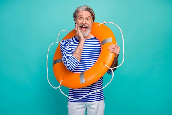 Foto do atraente funky envelhecido marinheiro boca aberta segurar segurança salvar vida boia mar oceano barco desgaste listrado marinheiro camisa calças brancas shorts isolado teal cor fundo — Fotografia de Stock