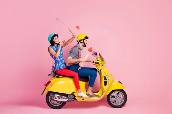 Full body profil boczny zdjęcie pozytywne amours dwie osoby podróż na szybki żółty chopper kobieta siedzieć strzelać strzałka w niebo nosić casual styl strój odizolowany pastelowy różowy kolor tło — Zdjęcie stockowe
