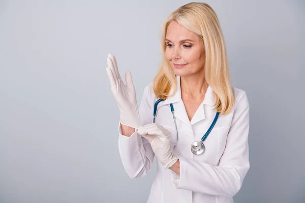 Portre niteliğindeki enfeksiyon uzmanı emekli kadın lastik eldivenler giyip Corona virüsü hastasını incelemeye hazır. Stetoskop beyaz önlük giyer. — Stok fotoğraf