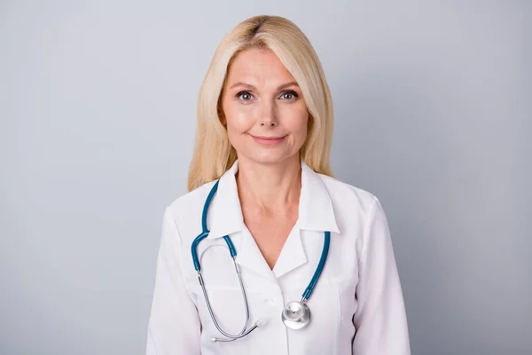 Tecrübeli kardiyolog doktor yaşlı kadının portresi, korona virüsü bulaşmasını önlediğini düşünüyor. Gri arkaplan üzerine beyaz önlük giy. — Stok fotoğraf