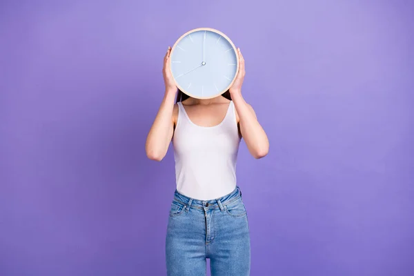 Portrét okouzlující dívka skrýt hlavu s kulatými hodinami hodinky show čas nosit dobrý vzhled oblečení izolované přes fialové barvy pozadí — Stock fotografie