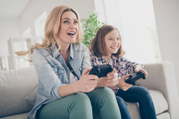 Foto de la señora rubia divertida doméstica mamá hija sentado cómodo sofá mantenga joystick jugando videojuegos estancia casa cuarentena de seguridad pasar el fin de semana juntos mejores amigos sala de estar en el interior — Foto de Stock