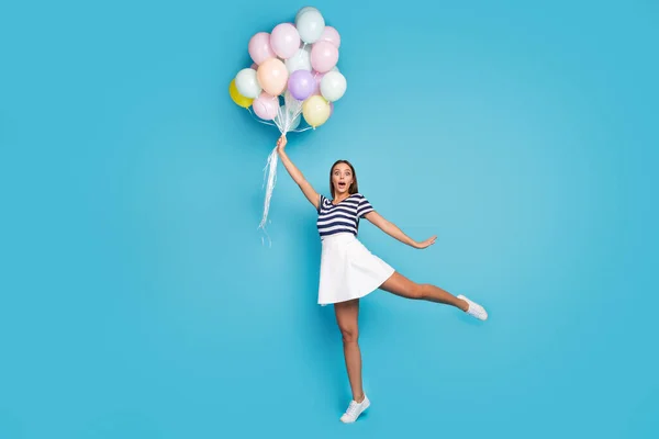 Ich fliege. Foto in voller Größe von schönen funky lady halten viele bunte Luftballons fliegen mit Wind weht tragen gestreifte T-Shirt weiße kurze Rockschuhe isoliert blauen Farbhintergrund — Stockfoto
