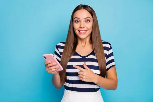 Foto de senhora alegre segurar telefone mão direcionando dedo inteligente telefone gerente de vendas tela aconselhando baixos preços do dispositivo usar listrado t-shirt saia branca isolado azul cor de fundo — Fotografia de Stock