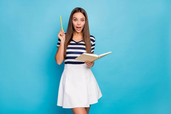 Foto de hermosa señora alegre celebrar diario copybook levantar pluma han pensamiento creativo inteligente estudiante abierto boca desgaste rayas camiseta blanca falda aislado color azul fondo — Foto de Stock