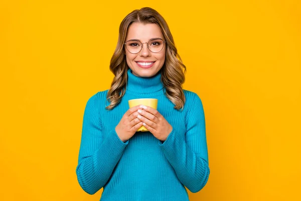 魅力的なかなり巻きビジネス女性の写真熱いお茶飲料カップを保持しますあなたの笑顔を楽しむ週末のレジャーウェア仕様ブルーセータータートルネック隔離された明るい黄色の背景 — ストック写真